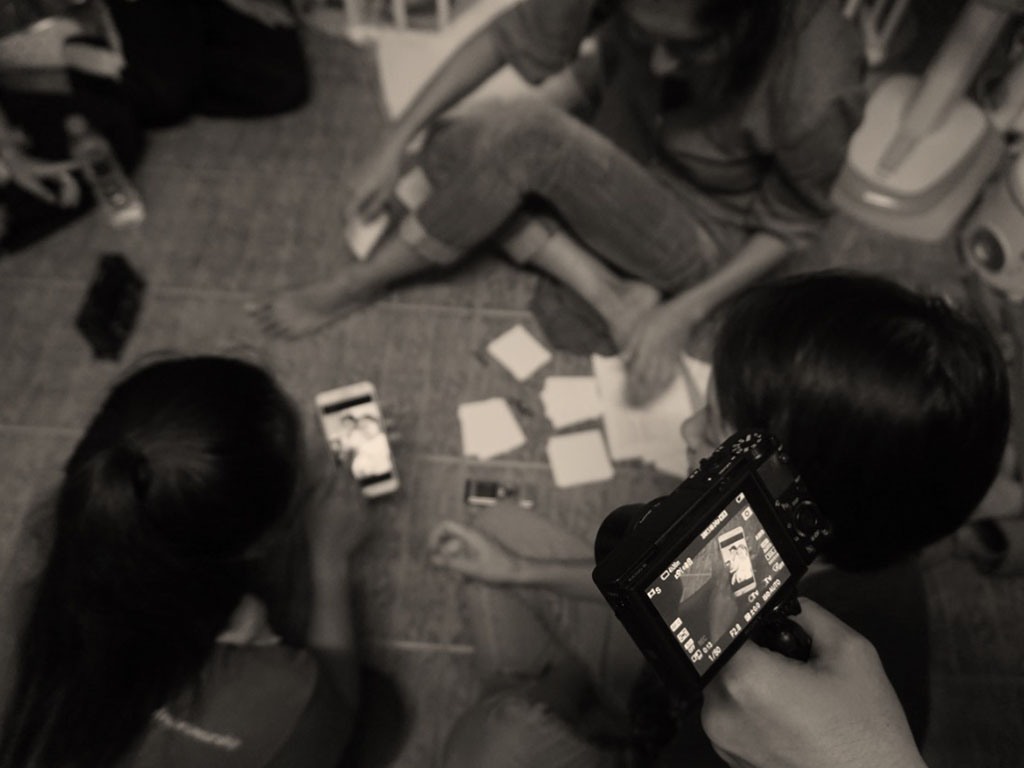 Overhead view of people collaborating on the floor with sticky notes and a camera, representing sharing research